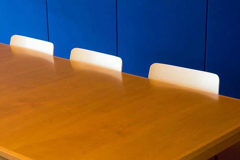 Een grote houten vergadertafel in een modern kantoor met comfortabele stoelen eromheen.